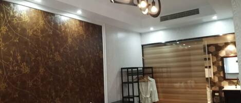 A modern hotel room with a bed, a robe, a wardrobe, and a bathroom visible through a sliding door.