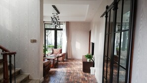 A hallway with a wooden floor, a staircase, a sofa, and a potted plant.