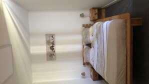 A narrow room with a bed, a wall-mounted lamp, and a small wooden cabinet. - APARTMENT 1.5 kms FROM THE LANDING BEACHES  (Tracy sur Mer)