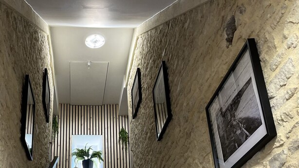A hallway with textured walls, framed photographs, and a door at the end. - APARTMENT 1.5 kms FROM THE LANDING BEACHES  (Tracy sur Mer)