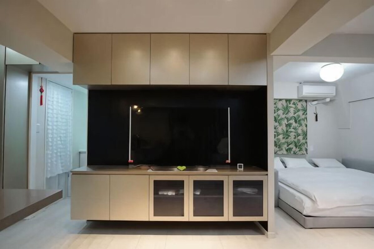 A modern room with a bed, a built-in TV, and a small desk area.