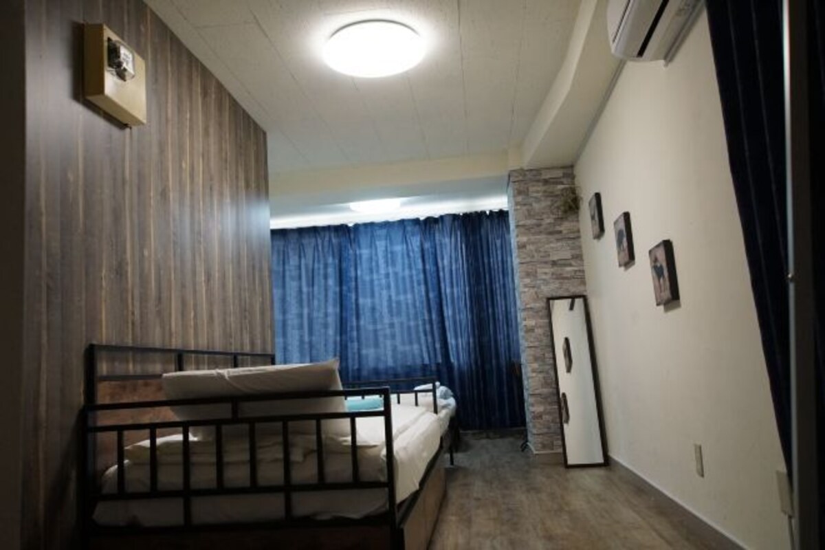 A room with a bed, a wardrobe, a mirror, and a window with curtains.