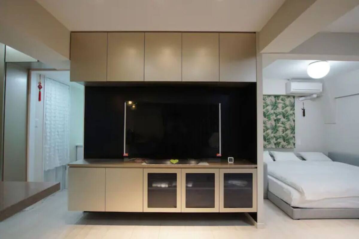 A modern bedroom with a bed, a built-in TV, and a wardrobe.