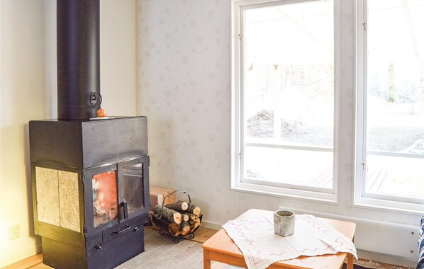 Ein Zimmer mit Kaminofen, einem Fenster mit Blick auf eine verschneite Landschaft und einem Tisch mit Tischdecke und Tasse.