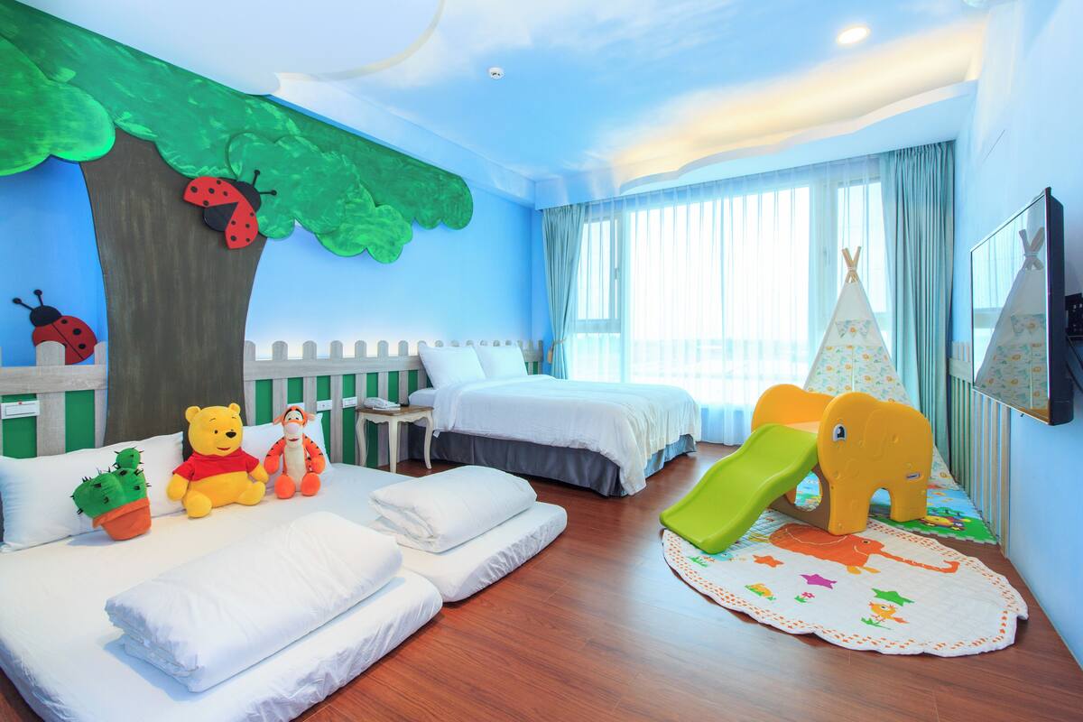 A children's room with a bed, a play area, and a window with curtains.