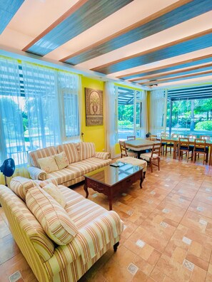 Amplia sala de estar con un conjunto de sofás, una mesa de comedor con sillas y vistas a zonas verdes.