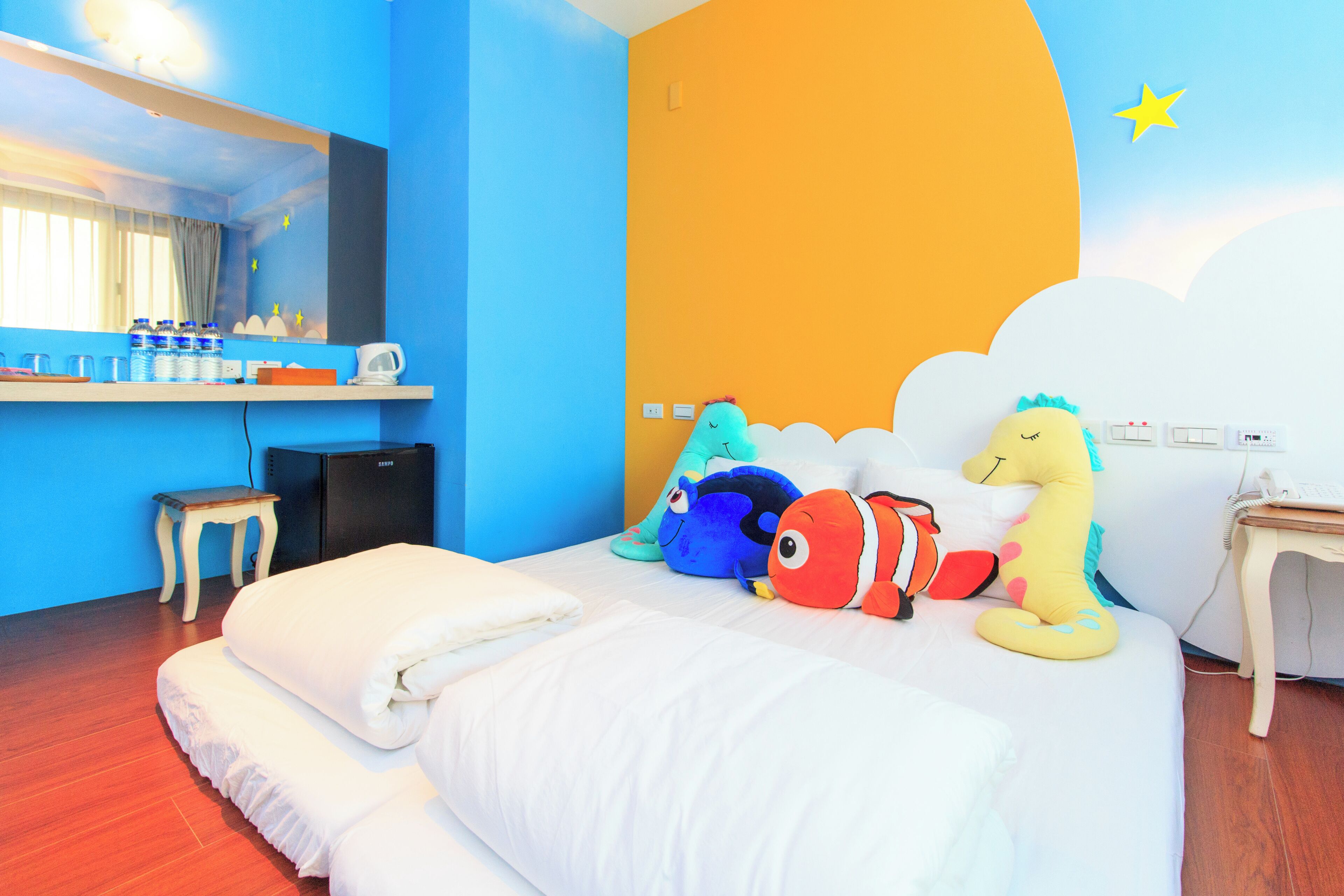 Ein Hotelzimmer mit Bett, Kissen, Schreibtisch mit Stuhl, einem kleinen Tisch und einem Spiegel.