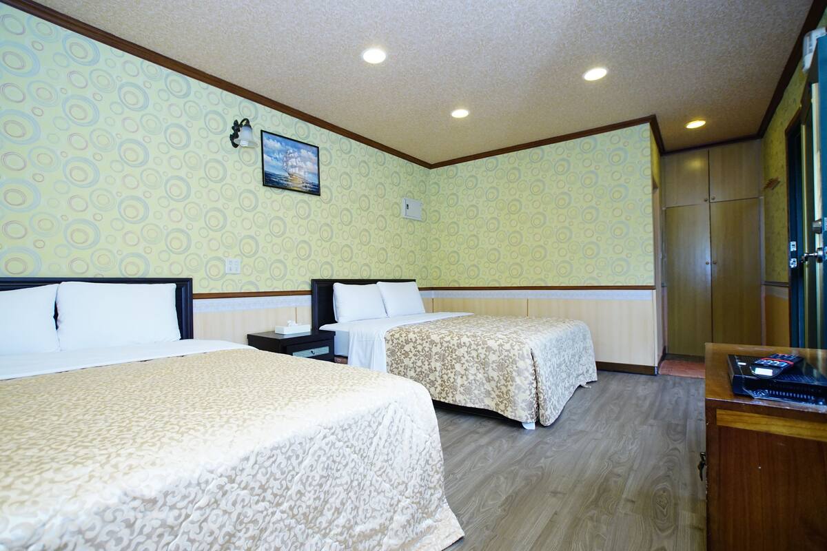Une chambre d’hôtel avec deux lits, un bureau et un petit téléviseur.