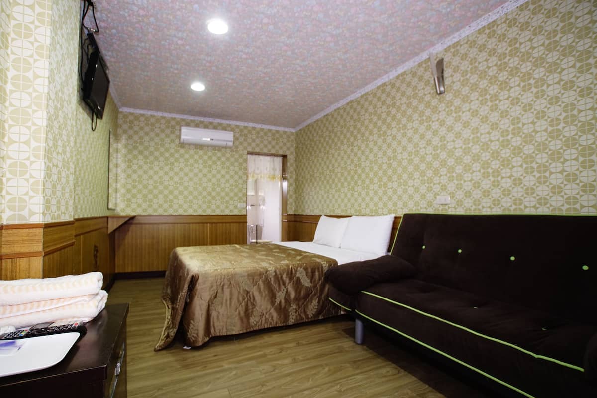 Une chambre d’hôtel comprenant un lit, un canapé, une armoire en bois et un téléviseur.