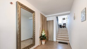 Ein Flur mit einem großen Spiegel, einem Blumentopf und einer Treppe, die zu einem Essbereich führt.