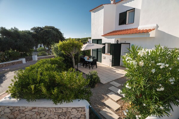 Ein modernes Haus mit Terrasse, Sitzgelegenheit im Freien und Garten.