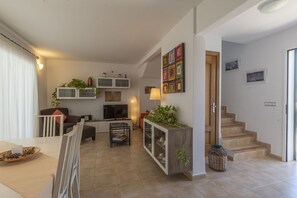 A modern living room with a sofa, TV, and a dining area with a table and chairs. - House with garden next to the beach with wifi (Es Mercadal)