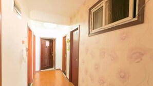 A hallway with wooden flooring and a floral-patterned wall. There are doors on both sides, and a window on the right wall. - Yi Xin Apartment - Hostel (Xi'an)