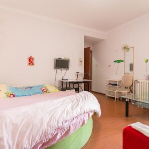 A bedroom with a bed, a desk, a chair, a mirror, and a radiator. - Yi Xin Apartment - Hostel (Xi'an)