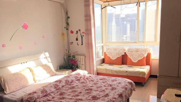 A bedroom with a bed, a sofa, a radiator, a window, and a cabinet. - Yi Xin Apartment - Hostel (Xi'an)