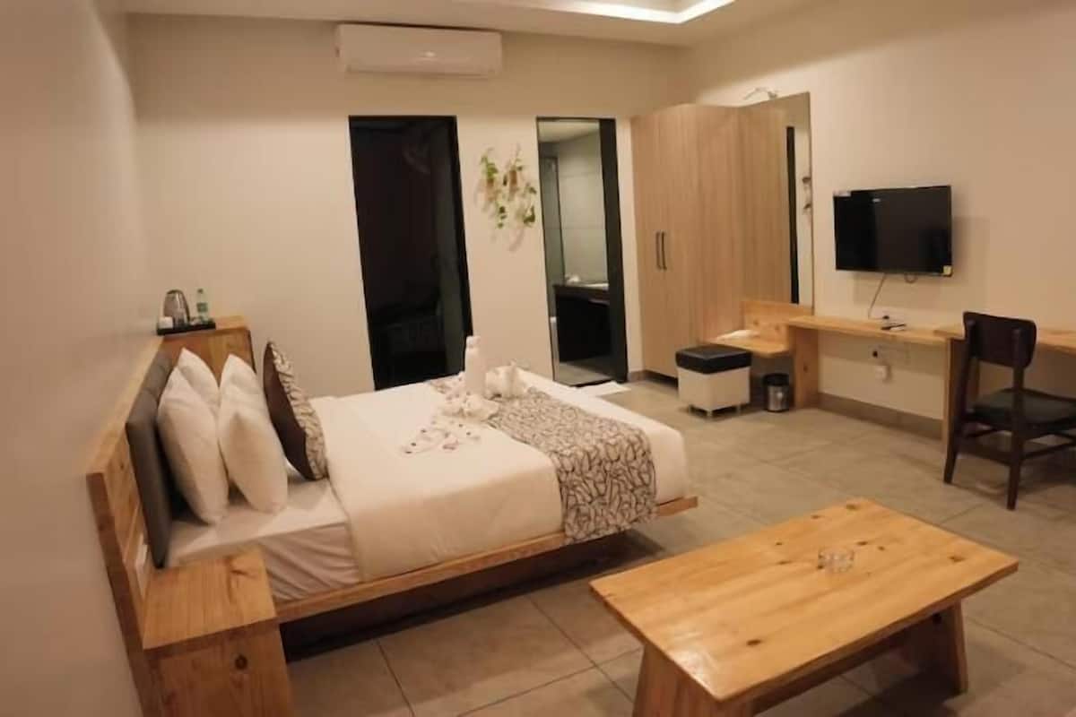 Un dormitorio moderno con cama, un escritorio de madera, una silla y un televisor.