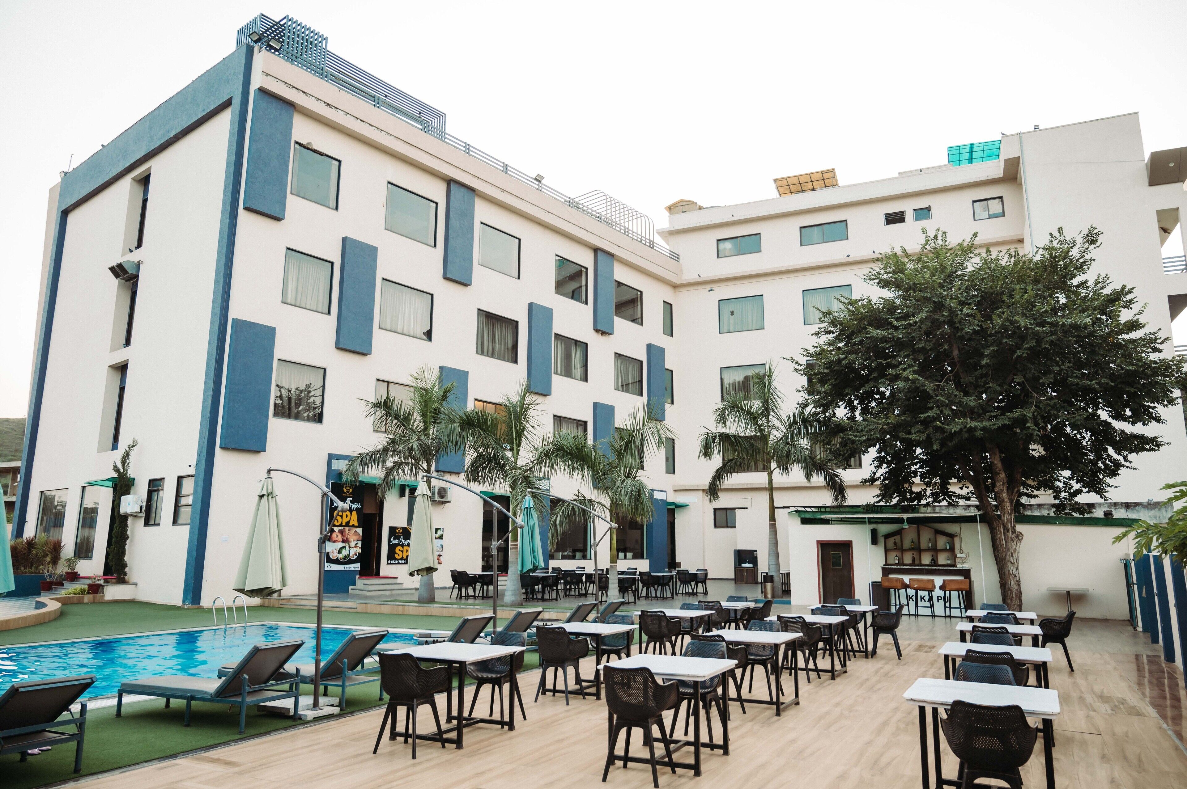 Un hotel con piscina, zona de estar exterior y un bar.