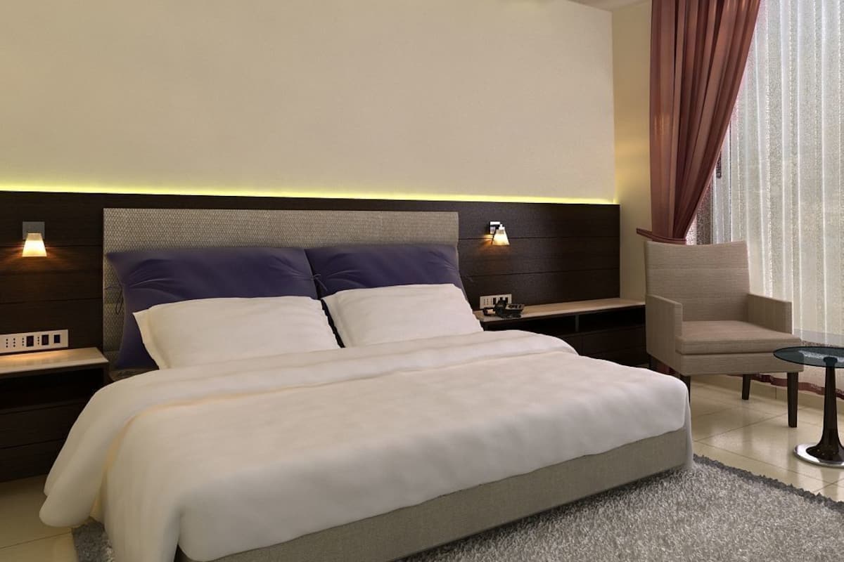 Habitación de hotel moderna con una cama grande, mesitas de noche, una silla y vistas al exterior.