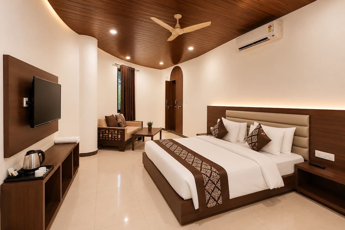 Una habitación de hotel moderna con una cama grande, televisión, sofá, mesa de centro y ventilador de techo.