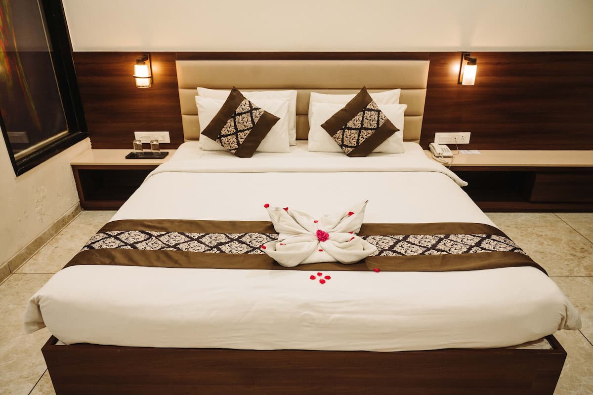 Una cama bien hecha con un adorno decorativo, dos mesitas de noche con lámparas y un cabecero de madera.