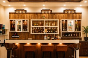 A bar area with wooden paneling, multiple liquor shelves, and bar stools. - Hotel the Hind (Abu Road)