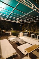 Una terraza en la azotea con varias camas, un comedor y vistas al cielo nocturno.
