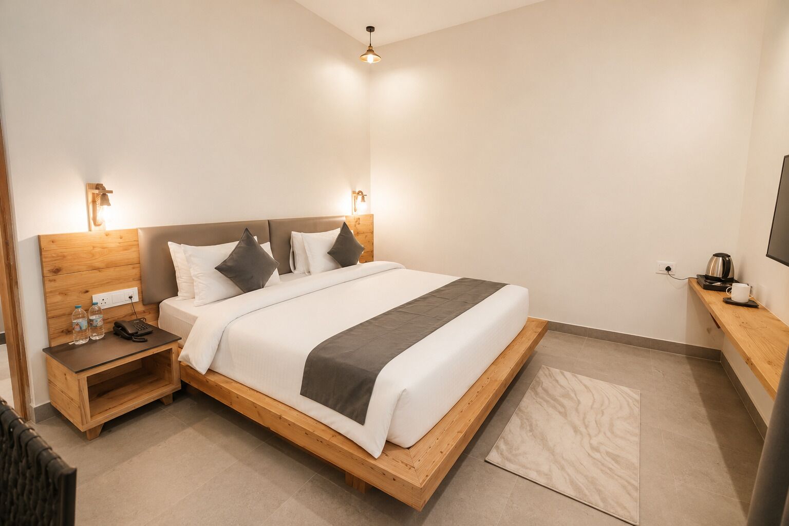 Una habitación de hotel con una cama de madera, mesitas de noche, un televisor y una cafetera.