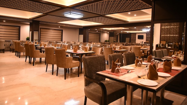 A spacious dining area with multiple tables and chairs, well-lit with ceiling lights, and a modern architectural design.