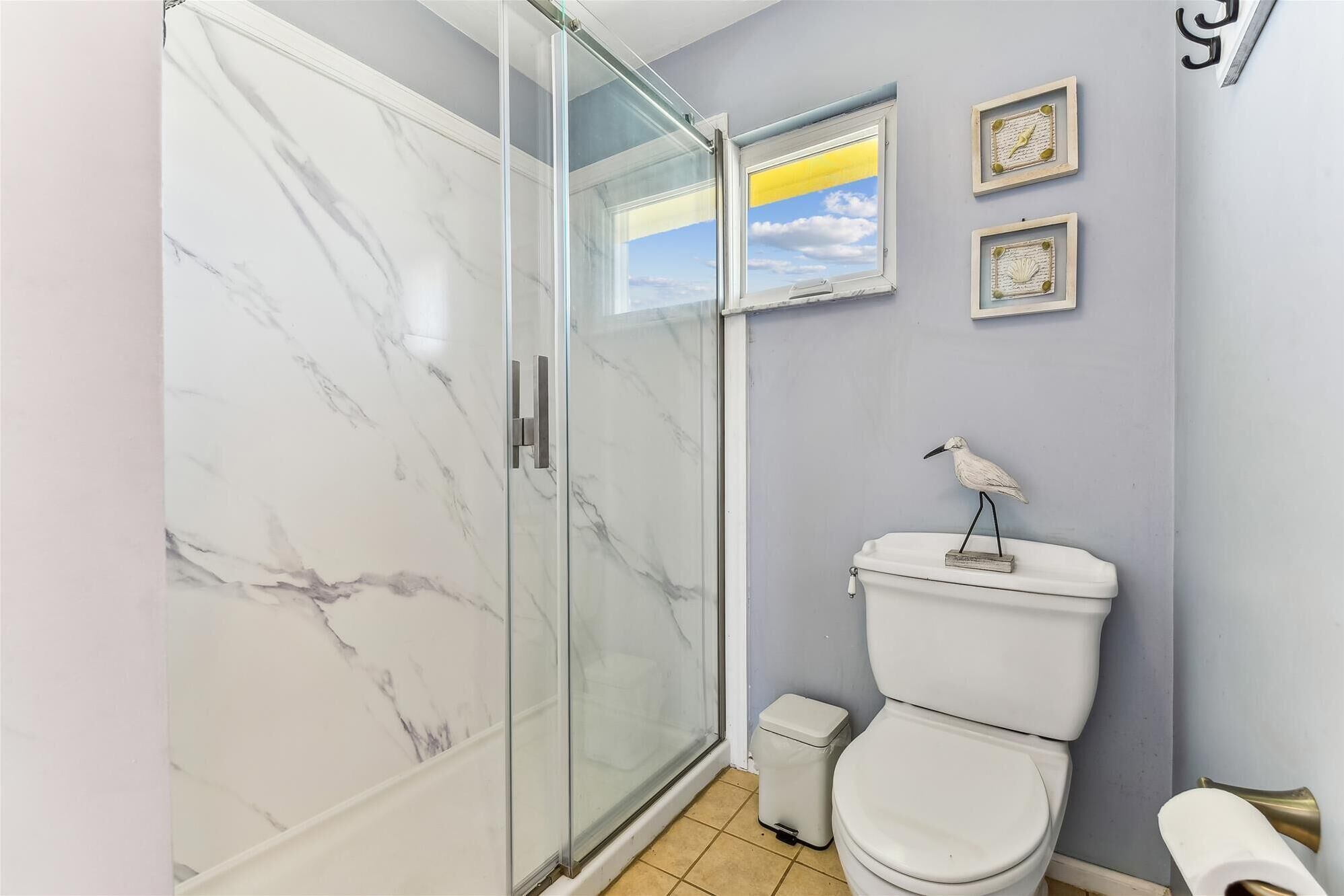 Une salle de bain avec une douche à parois de verre, des toilettes et des éléments décoratifs sur les murs.
