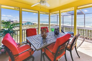 Une terrasse couverte, dotée d’une table et de chaises, qui offre une vue sur la plage.