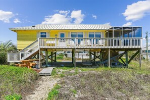 Un bâtiment jaune doté d’un balcon, d’une terrasse en bois et d’un espace abrité avec des bancs.