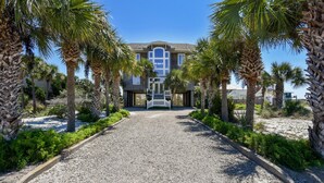 A two-story building with a gravel driveway leading to a gated entrance. - You will delight in the fabulous gulf views from this elegant, Nantucket style beach home! (St. George Island)