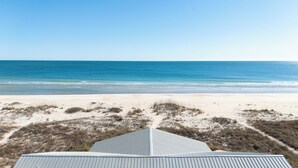 Une vue sur la plage, avec un ciel dégagé, une plage de sable et des dunes.