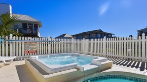A swimming pool with a hot tub, surrounded by a white picket fence, with houses in the background. - LEAVE THE city behind and enjoy your escape in this urban designed beach home. (St. George Island)