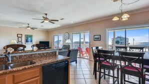 A kitchen with granite countertops, a dishwasher, and a dining area with wooden chairs and a table. - LEAVE THE city behind and enjoy your escape in this urban designed beach home. (St. George Island)