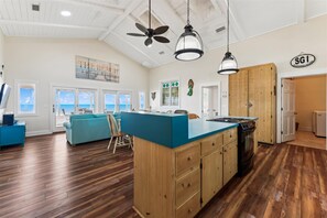 A spacious kitchen with wooden cabinets, a central island, and a view of the ocean through large windows.