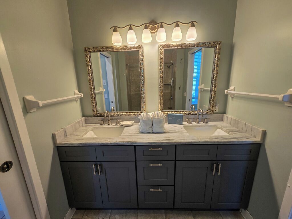 A bathroom with a double vanity, two sinks, and a large mirror with light fixtures.