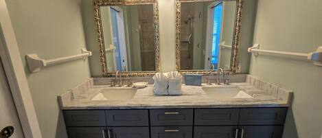 A bathroom with a double vanity, two sinks, and a large mirror with light fixtures.