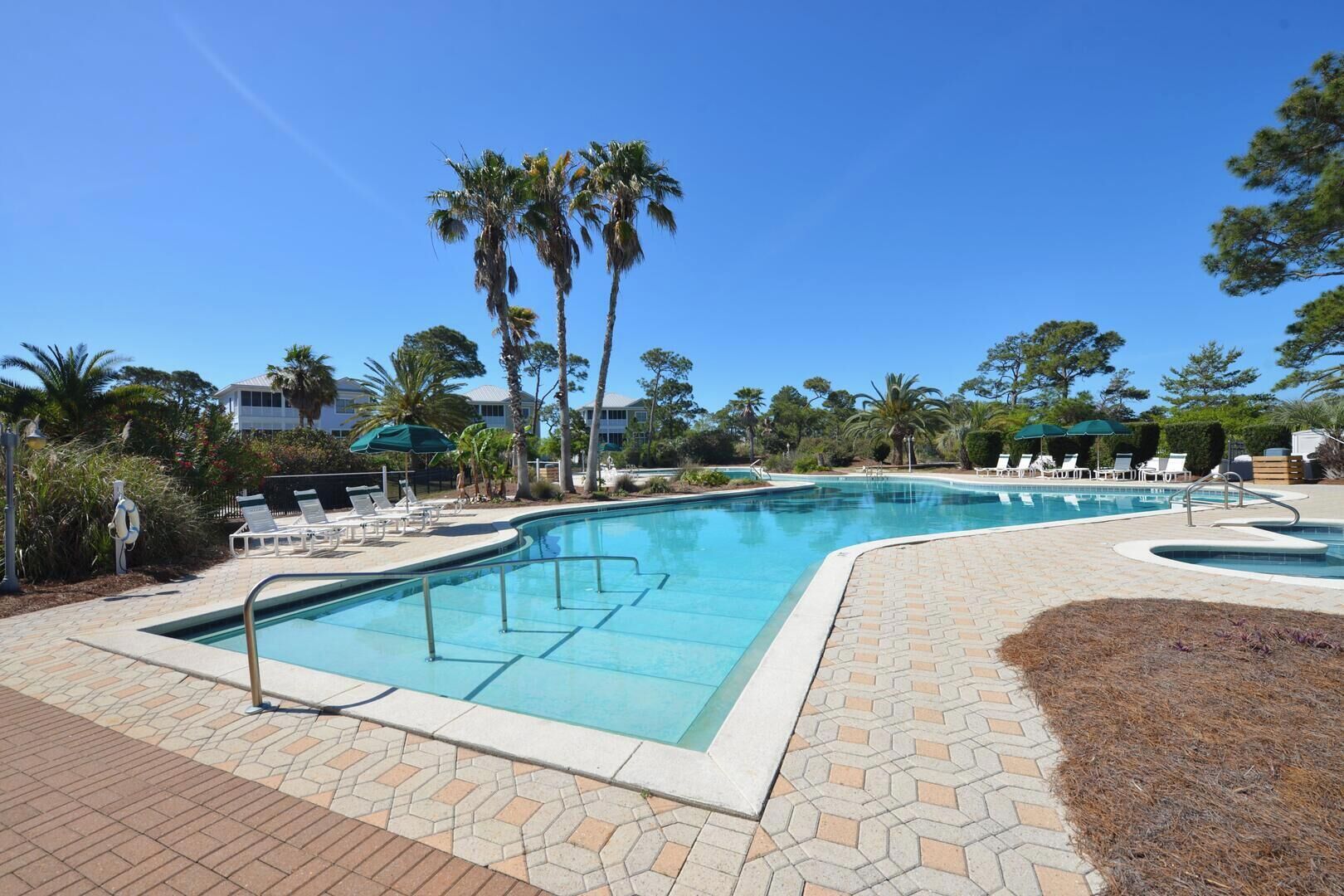 A pool area with lounge chairs and palm trees.