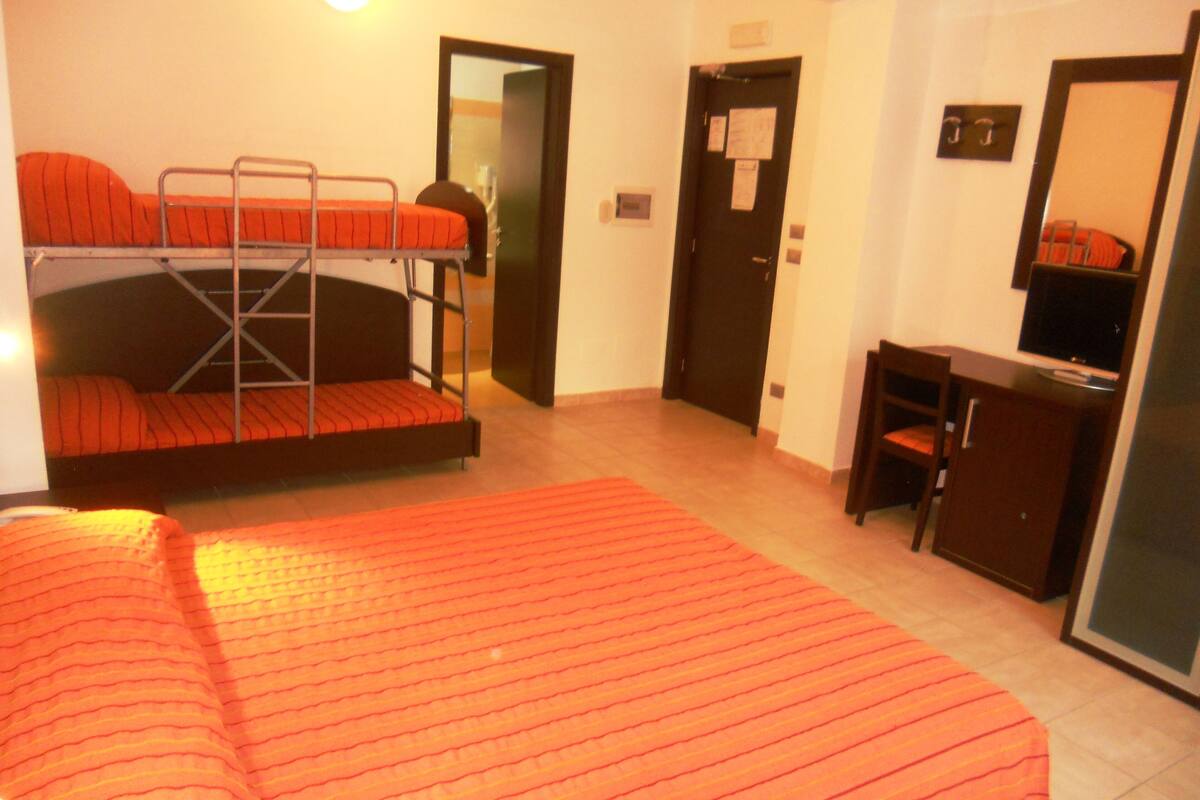 Une chambre avec un lit superposé, un bureau, une chaise et un téléviseur.
