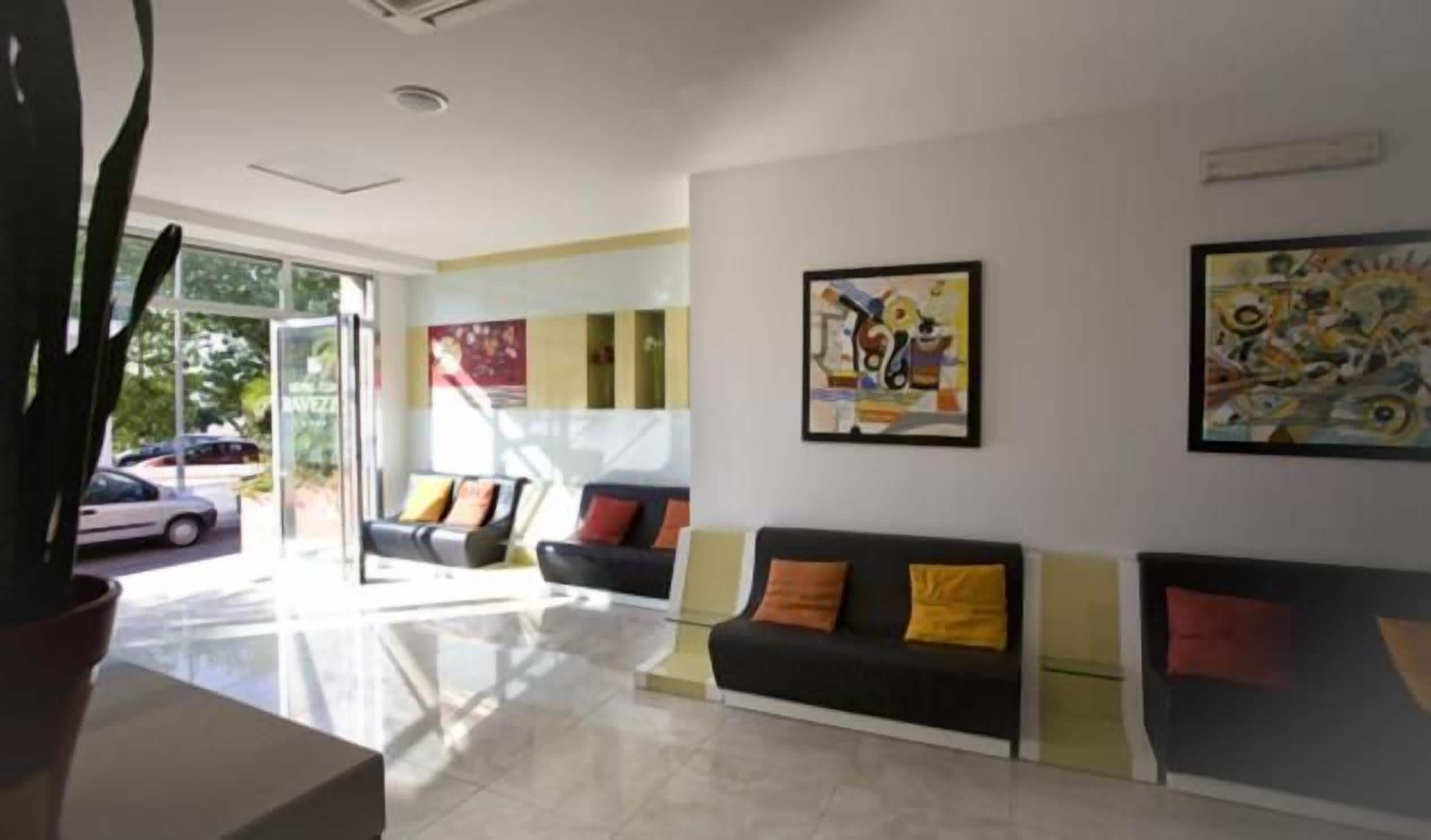 A reception area with a black sofa, a cactus, and artwork on the wall.