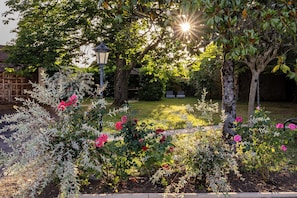 Un jardin agrémenté de plantes et d’arbres en fleurs, une clôture en bois et un lampadaire.