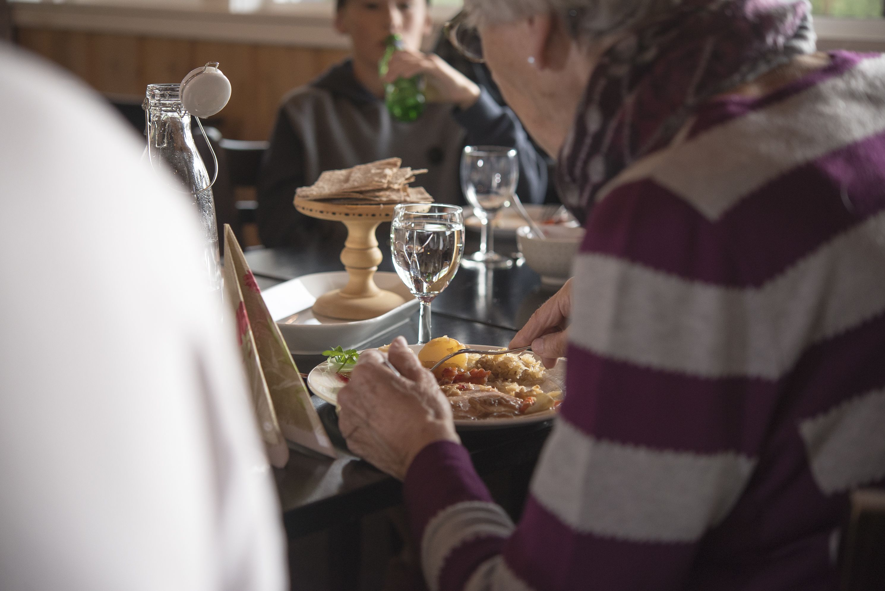 A dining table with plates of food, a wine glass, and a bottle with a cork.