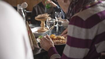 A dining table with plates of food, a wine glass, and a bottle with a cork.
