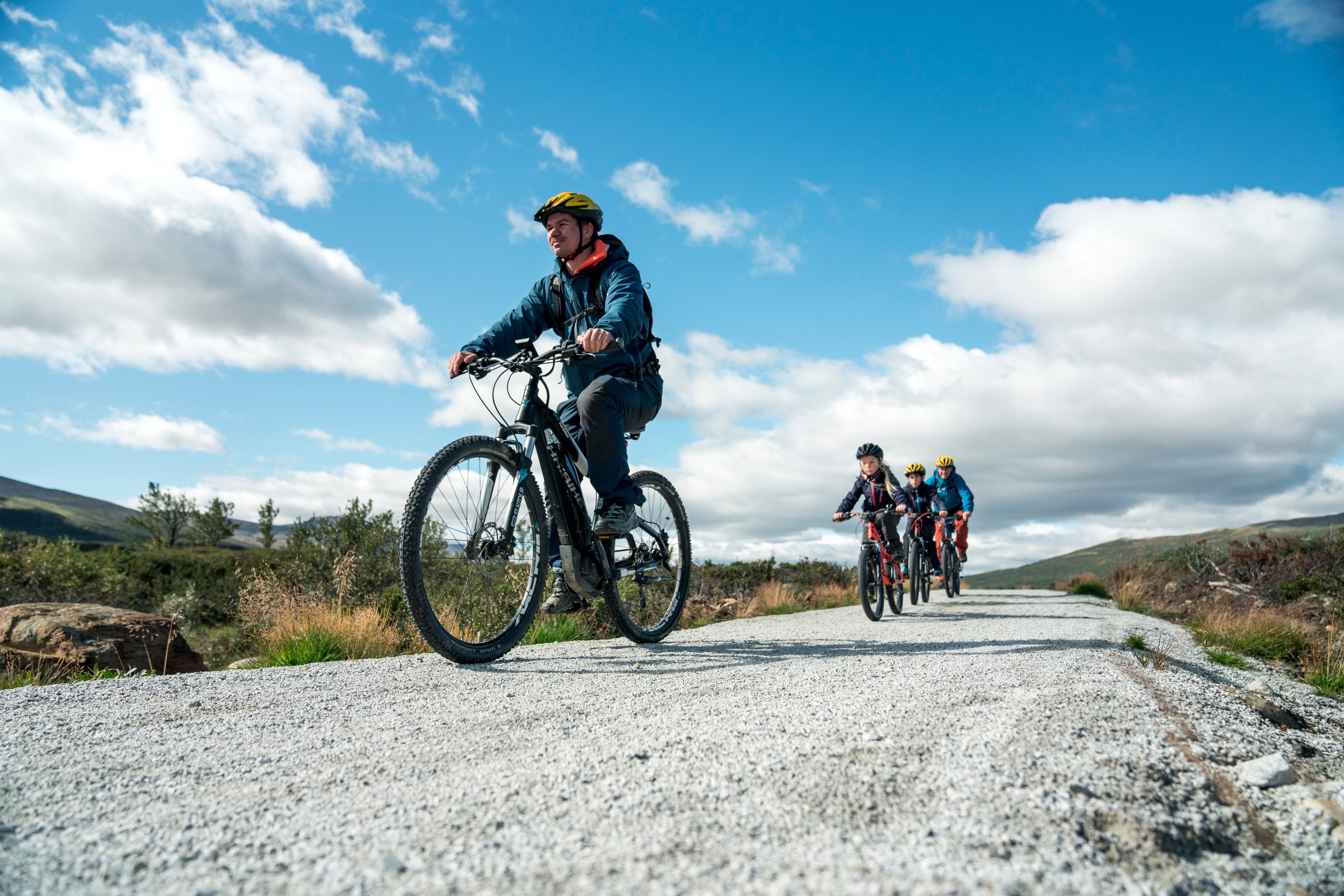 A gravel road with cyclists in a mountainous area.