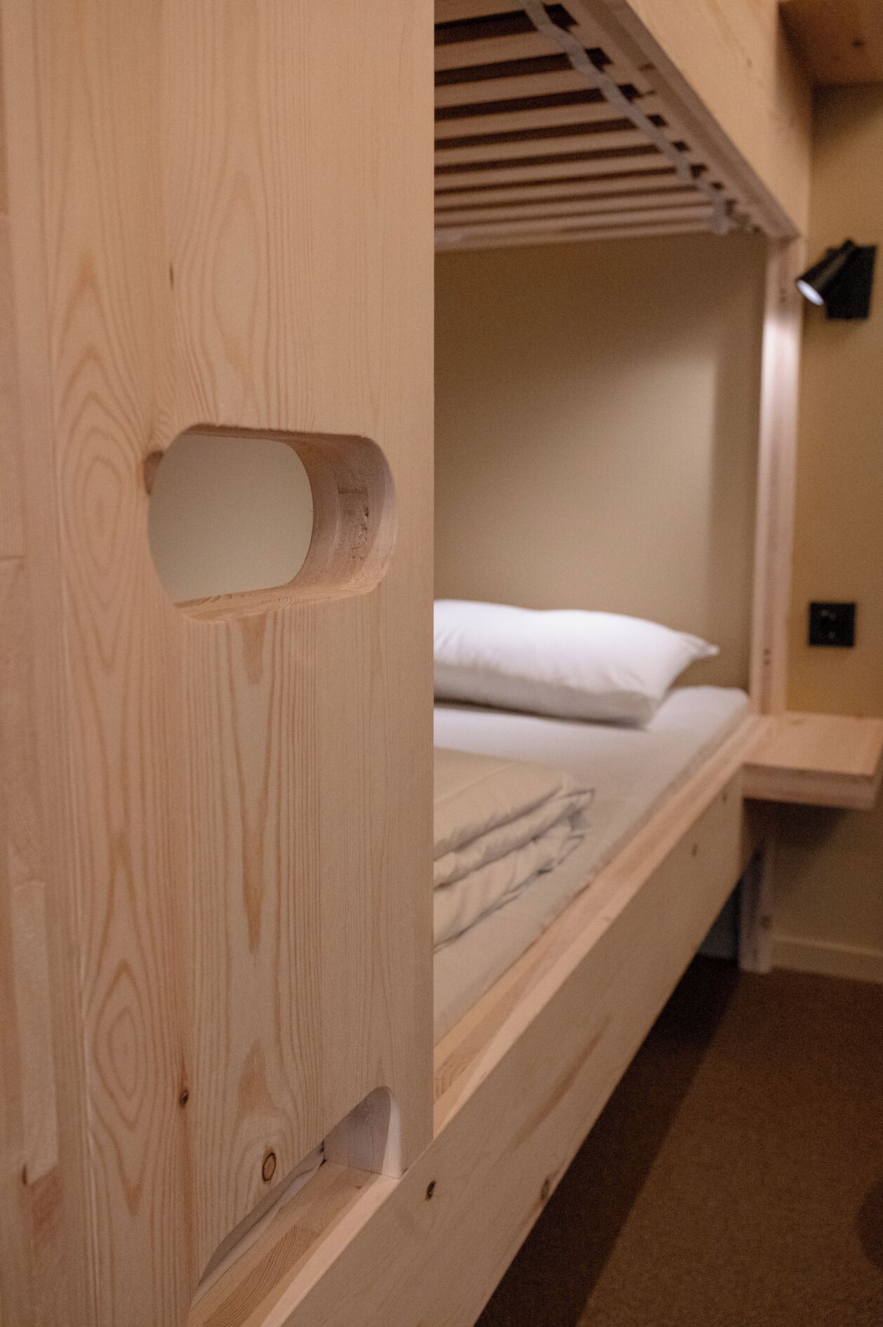 Una cama litera con cabecera de madera y una pequeña repisa.