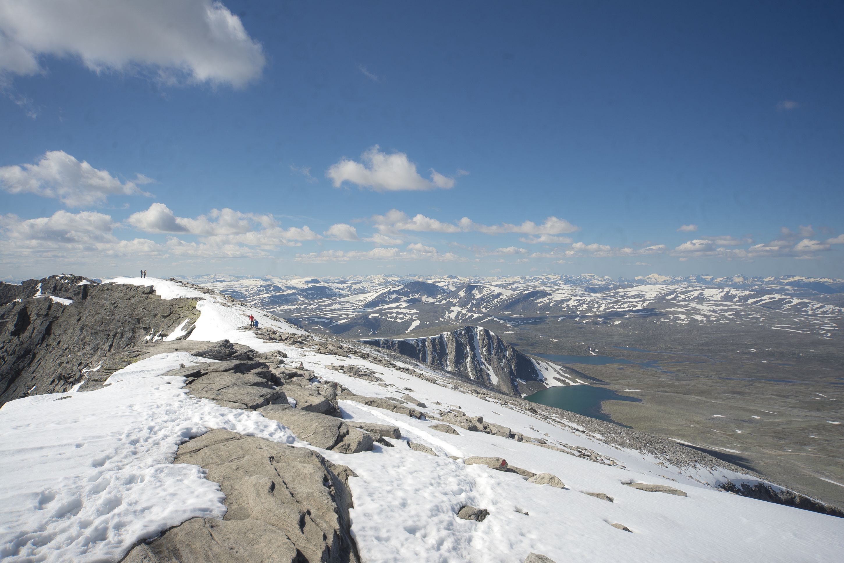 A snow-covered mountain ridge with rocky terrain and distant mountain peaks.