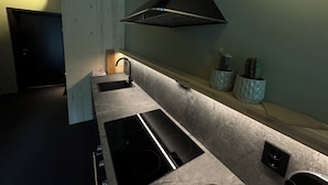 A modern kitchen with a black stove, a sink, and a wooden countertop. - Trolltun Hotel (Dovre)