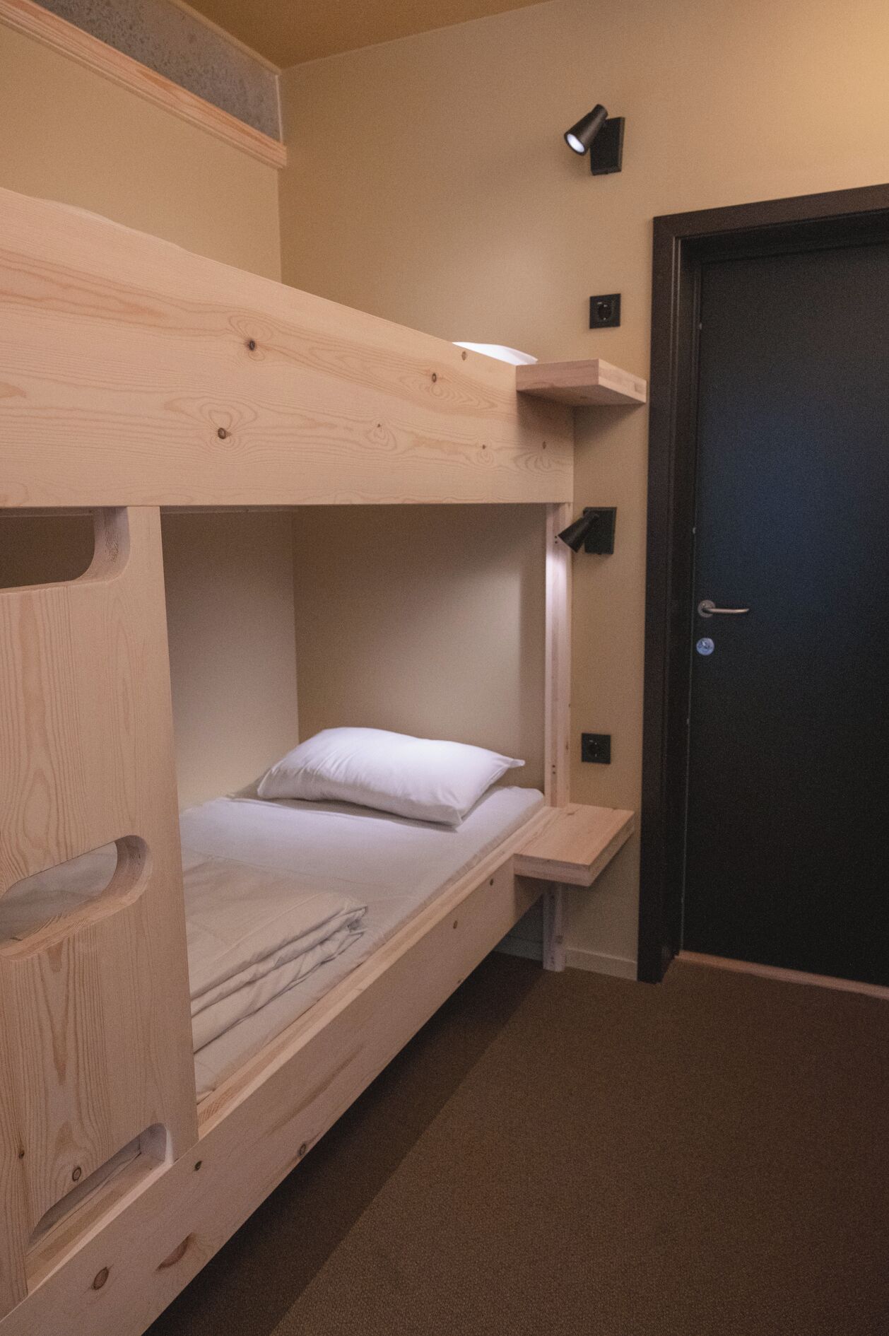 Een stapelbed met een klein bureau en een deur in een kamer.
