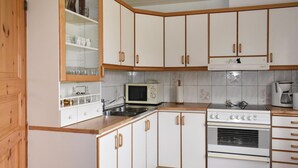 A kitchen with white cabinets, a microwave, a stove, and a coffee maker. - Amazing home in Borrby with WiFi (Borrby)